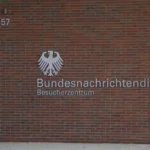 Außenansicht des Besucherzentrums des Bundesnachrichtendienstes mit Adler-Emblem und Schriftzug an einer Backsteinwand.