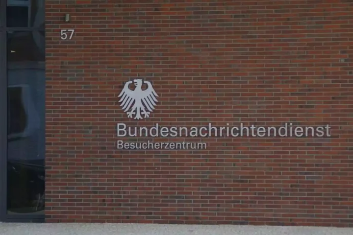 Außenansicht des Besucherzentrums des Bundesnachrichtendienstes mit Adler-Emblem und Schriftzug an einer Backsteinwand.