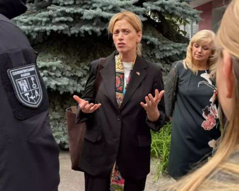 Karin Prien spricht im Freien mit mehreren Personen und gestikuliert dabei.
