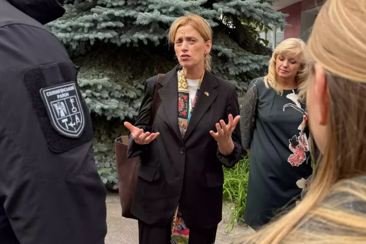Karin Prien spricht im Freien mit mehreren Personen und gestikuliert dabei.