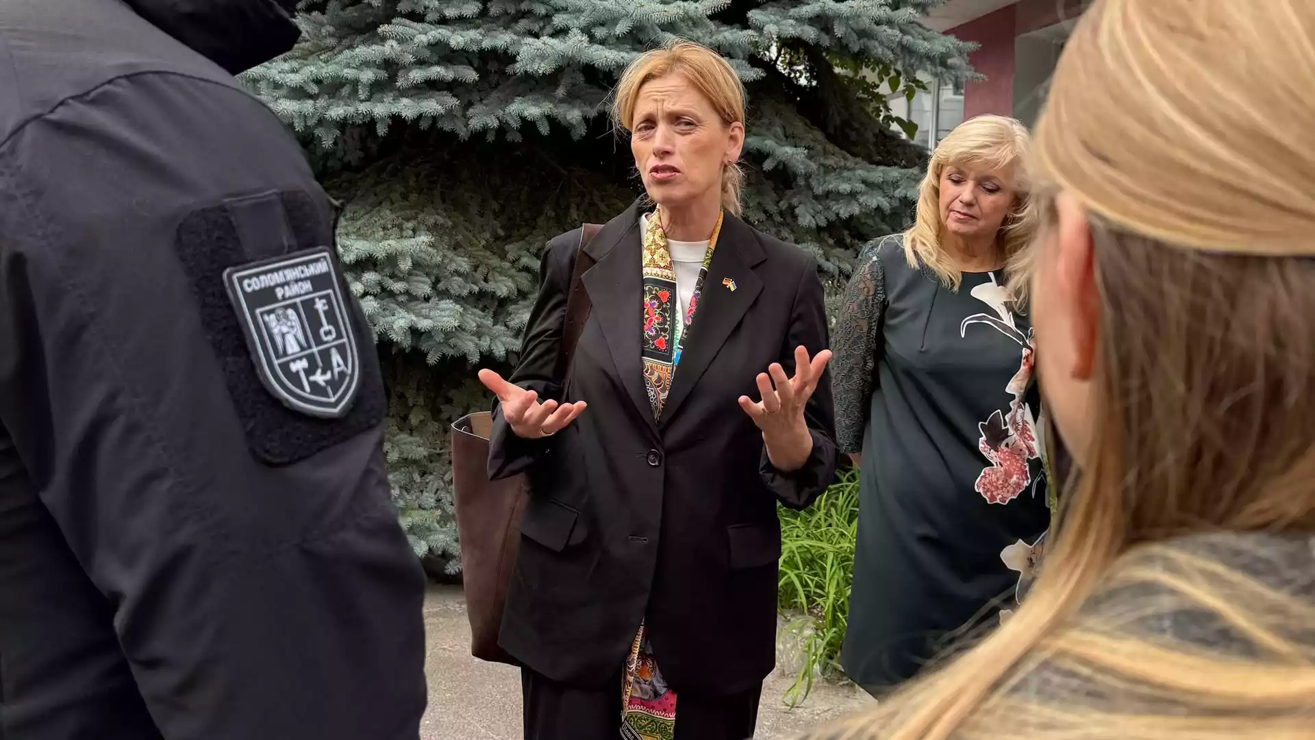 Karin Prien spricht im Freien mit mehreren Personen und gestikuliert dabei.