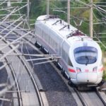 Ein ICE fährt auf einer elektrifizierten Bahnstrecke unter Oberleitungen.