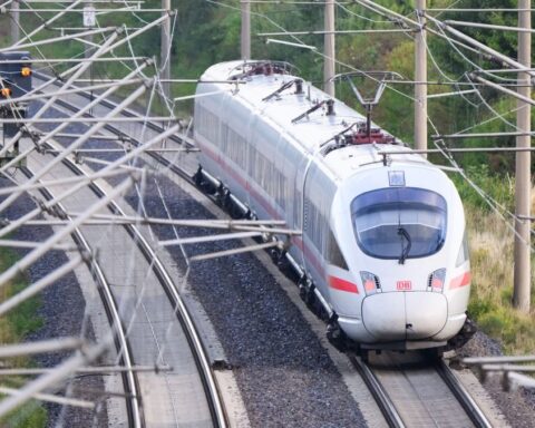 Ein ICE fährt auf einer elektrifizierten Bahnstrecke unter Oberleitungen.