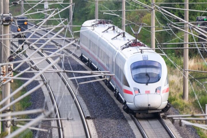 Ein ICE fährt auf einer elektrifizierten Bahnstrecke unter Oberleitungen.