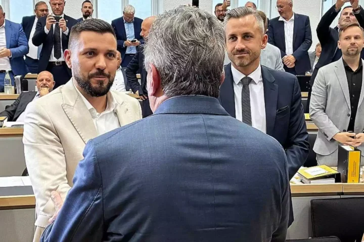 Mehrere Politiker stehen und sprechen in einem Sitzungssaal des Landtags.
