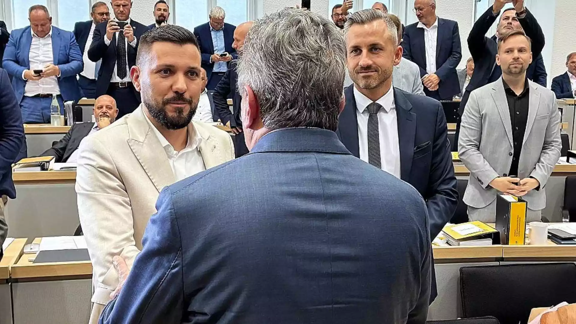 Mehrere Politiker stehen und sprechen in einem Sitzungssaal des Landtags.