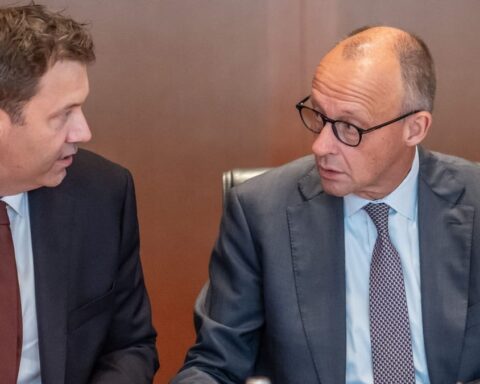 Zwei Männer im Anzug sprechen in einem Besprechungsraum miteinander.