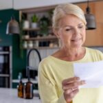 Ältere Frau liest ein Papier in einer modernen Küche.