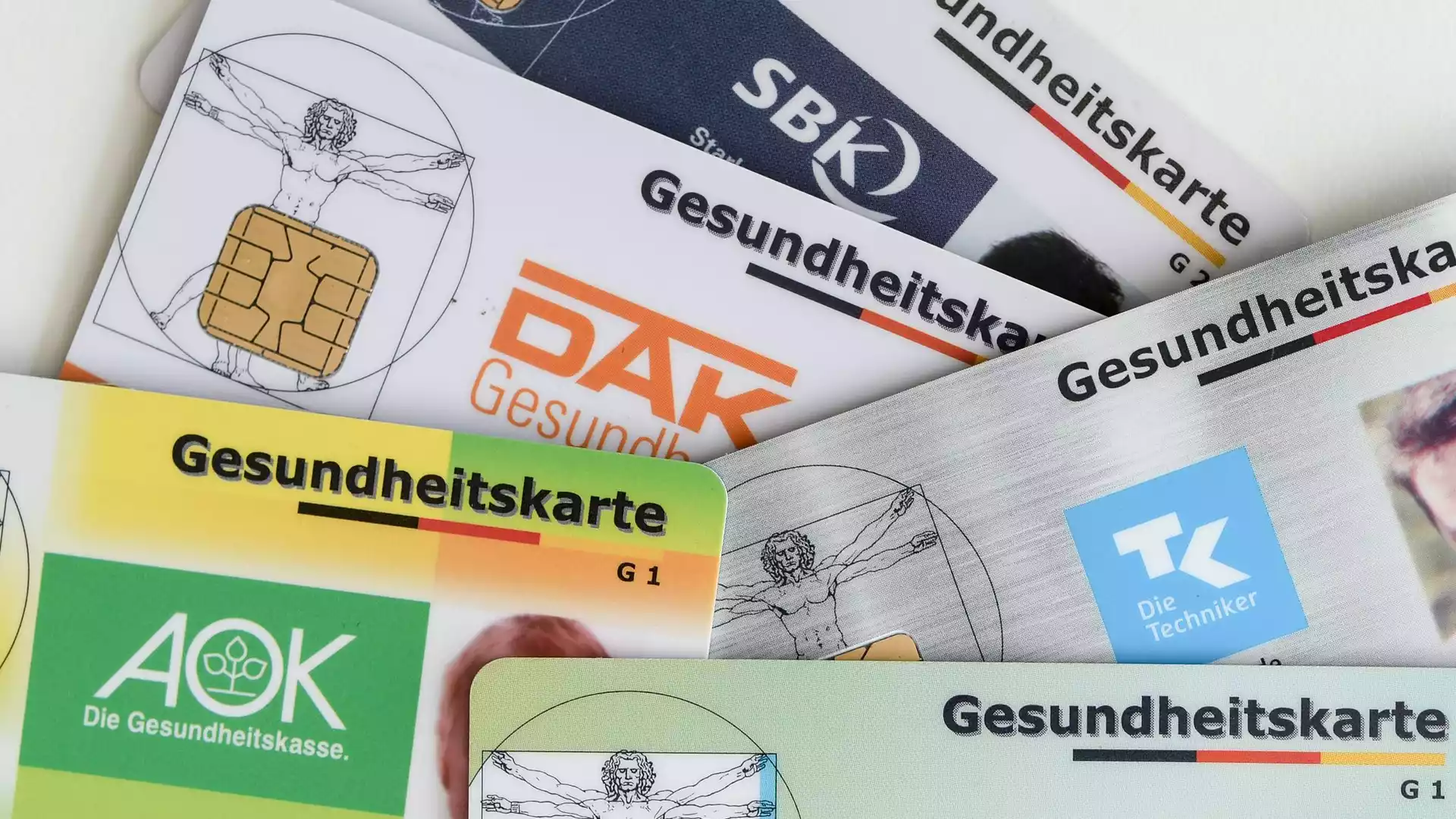 Mehrere deutsche Gesundheitskarten verschiedener Krankenkassen liegen übereinander.
