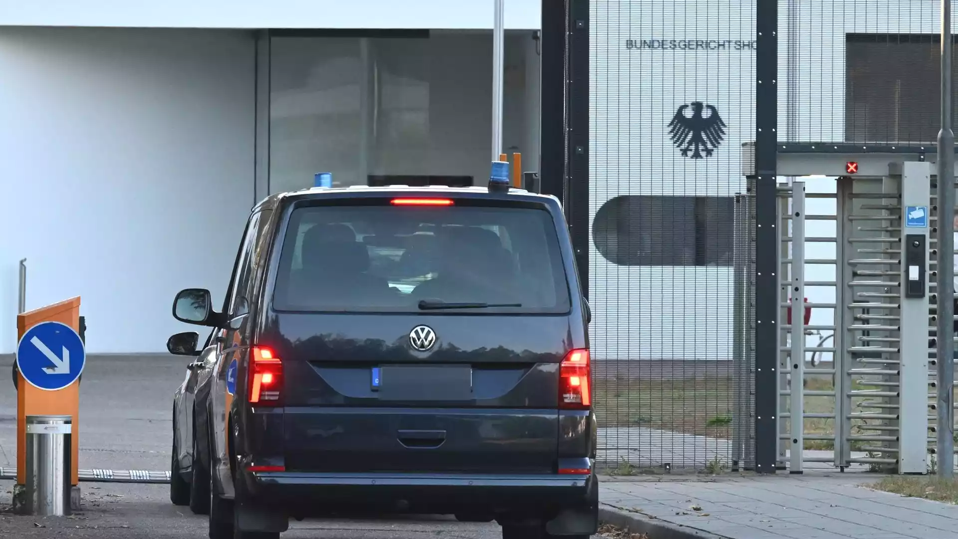 Bundesanwaltschaft lässt Haftbefehl gegen Ex-BND-Präsident Hanning vollziehen 1 Ein dunkler VW fährt vor einem gesicherten Tor mit Bundesadler an einem Behördengebäude vor.