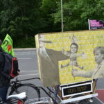 Demonstrierende mit Fahrrädern und Protestschildern an einer Straße in Berlin.