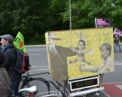 Demonstrierende mit Fahrrädern und Protestschildern an einer Straße in Berlin.