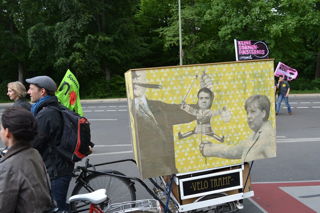 Demonstrierende mit Fahrrädern und Protestschildern an einer Straße in Berlin.