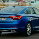 Blauer Hyundai Sonata von hinten an einer Uferstraße.