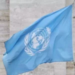 Blaue Flagge der Vereinten Nationen vor einem Gebäude.