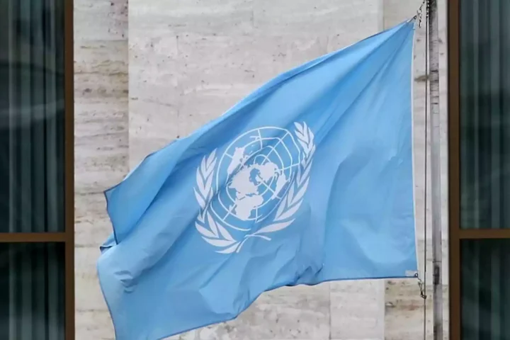 Blaue Flagge der Vereinten Nationen vor einem Gebäude.