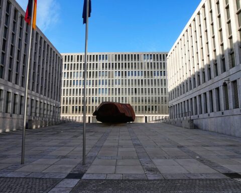 Blick in den Innenhof des Bundesnachrichtendienstes mit Fahnenmasten und moderner Gebäudefassade.