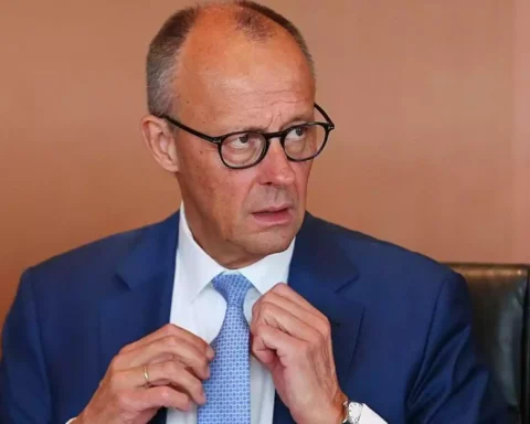 Mann im blauen Anzug und mit Brille richtet seine Krawatte.