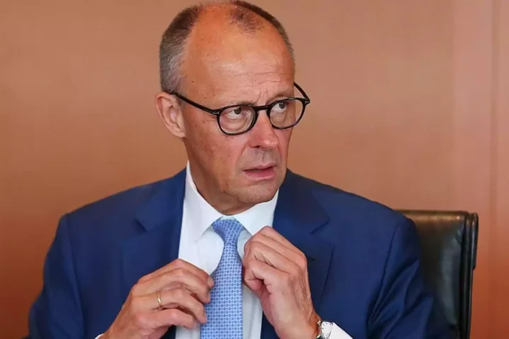 Mann im blauen Anzug und mit Brille richtet seine Krawatte.