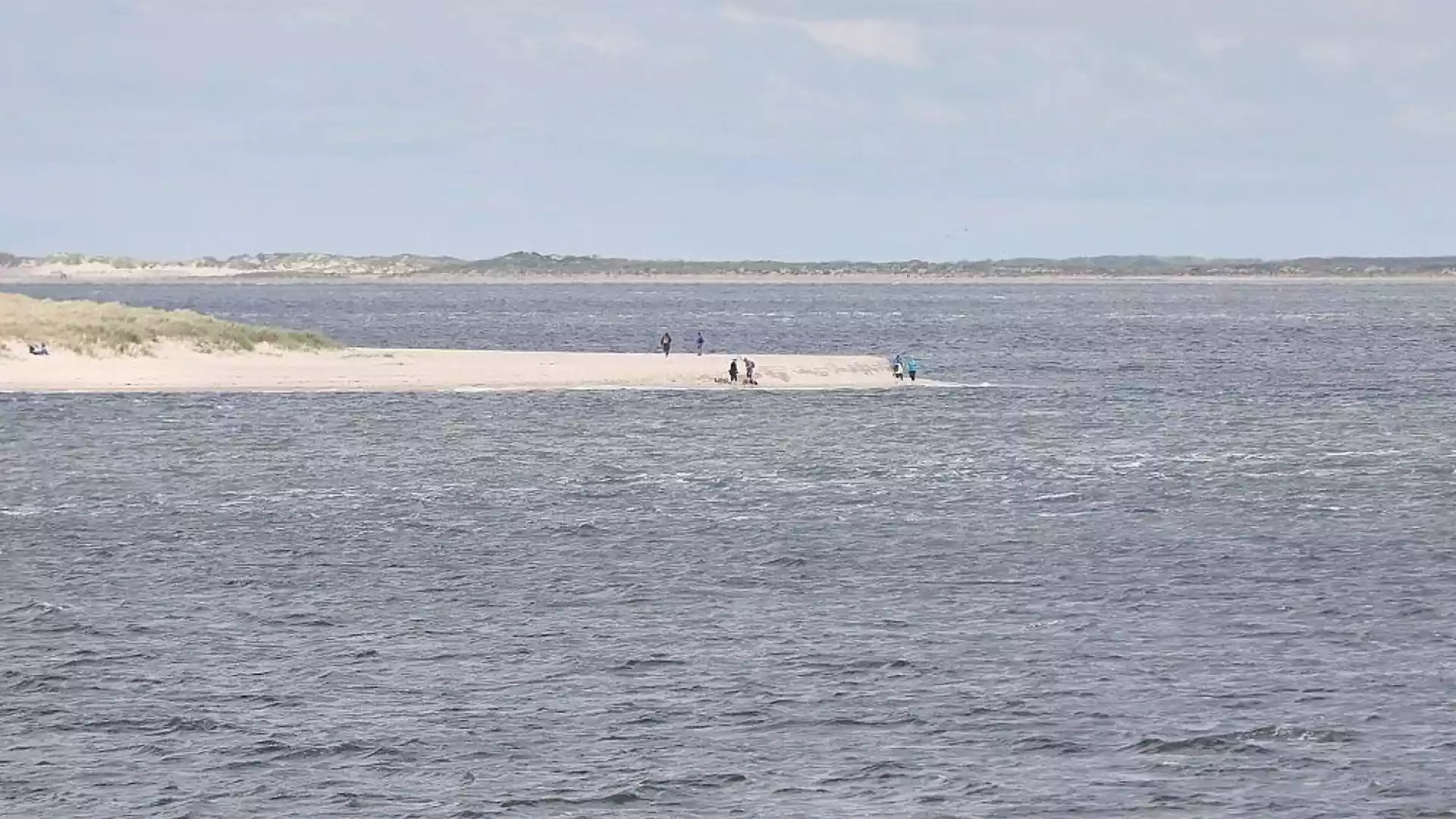 Blick auf eine kleine Sandbank in der Nordsee mit einigen Menschen im Wasser.