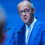 Friedrich Merz spricht in einem blauen Anzug an einem Rednerpult.