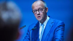 Friedrich Merz spricht in einem blauen Anzug an einem Rednerpult.