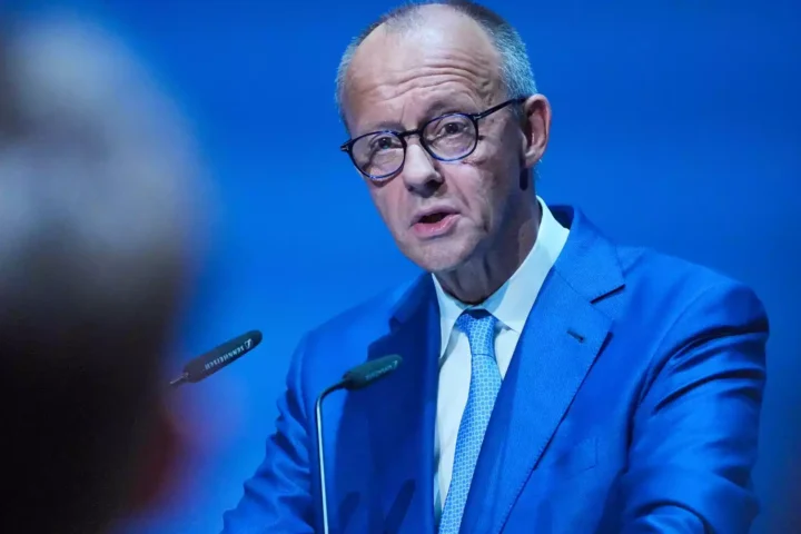 Friedrich Merz spricht in einem blauen Anzug an einem Rednerpult.