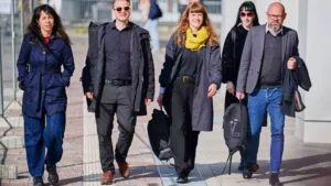 Mehrere Politiker gehen gemeinsam auf einem Gehweg im Freien.