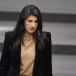 Eine Politikerin steht im Plenarsaal vor einem grauen Hintergrund.