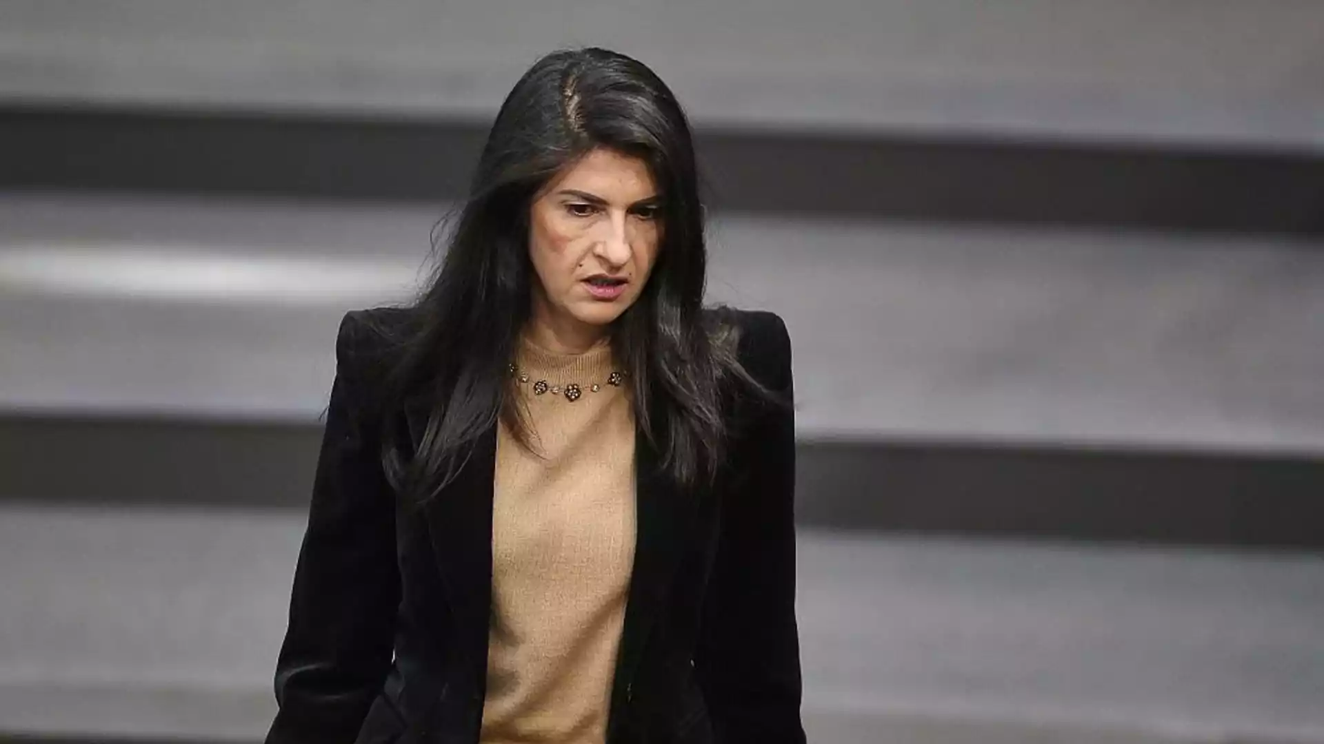 Eine Politikerin steht im Plenarsaal vor einem grauen Hintergrund.