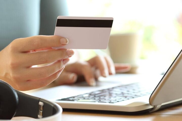 Hand hält eine Bankkarte vor einem Laptop beim Online-Banking.