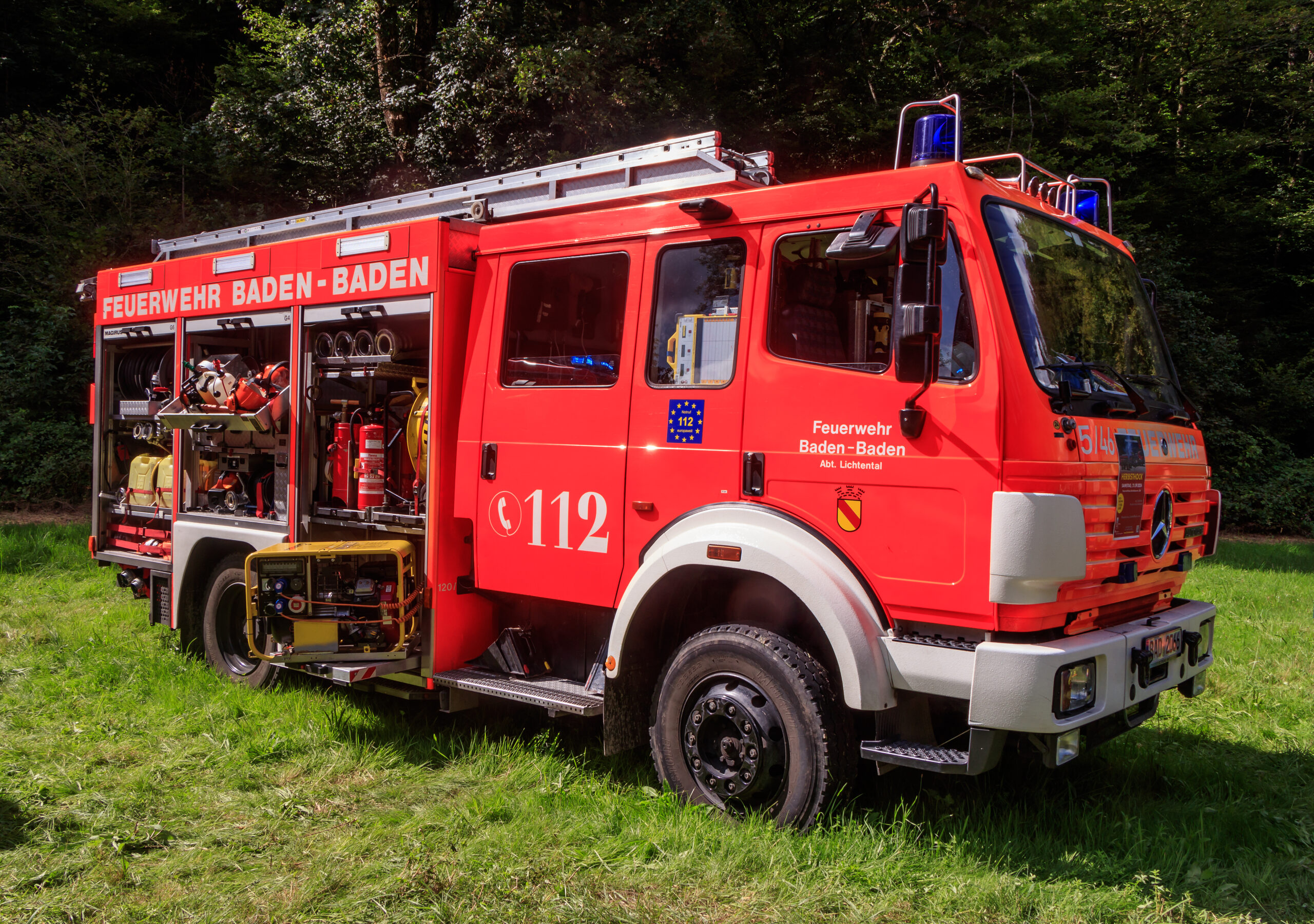 Rotes Feuerwehrfahrzeug der Feuerwehr Baden-Baden auf einer Wiese im Wald.
