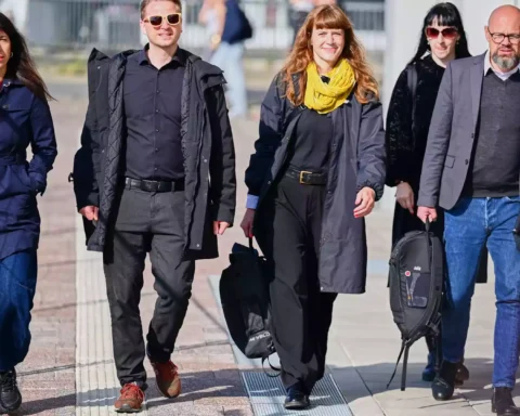 Vier Personen gehen gemeinsam auf einem Gehweg im Freien.