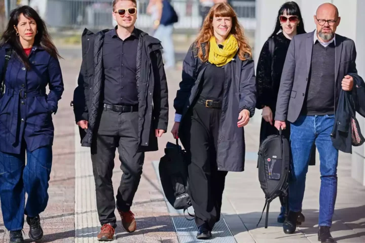 Vier Personen gehen gemeinsam auf einem Gehweg im Freien.