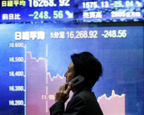 Silhouette eines Mannes vor einer Börsentafel mit fallendem Kursverlauf des Nikkei in Japan.