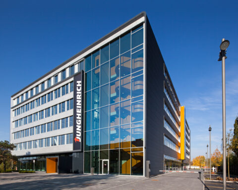 Jungheinrich-Gebäude mit Glasfassade und Firmenlogo bei klarem Himmel.