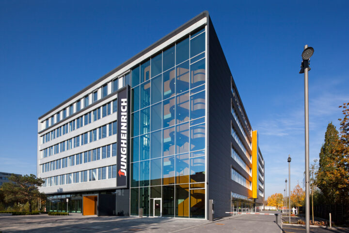Jungheinrich-Gebäude mit Glasfassade und Firmenlogo bei klarem Himmel.