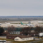 Mehrere Ryanair-Flugzeuge stehen auf dem Vorfeld eines Flughafens mit Start- und Landebahn im Hintergrund.