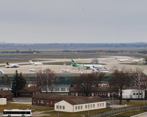 Mehrere Ryanair-Flugzeuge stehen auf dem Vorfeld eines Flughafens mit Start- und Landebahn im Hintergrund.