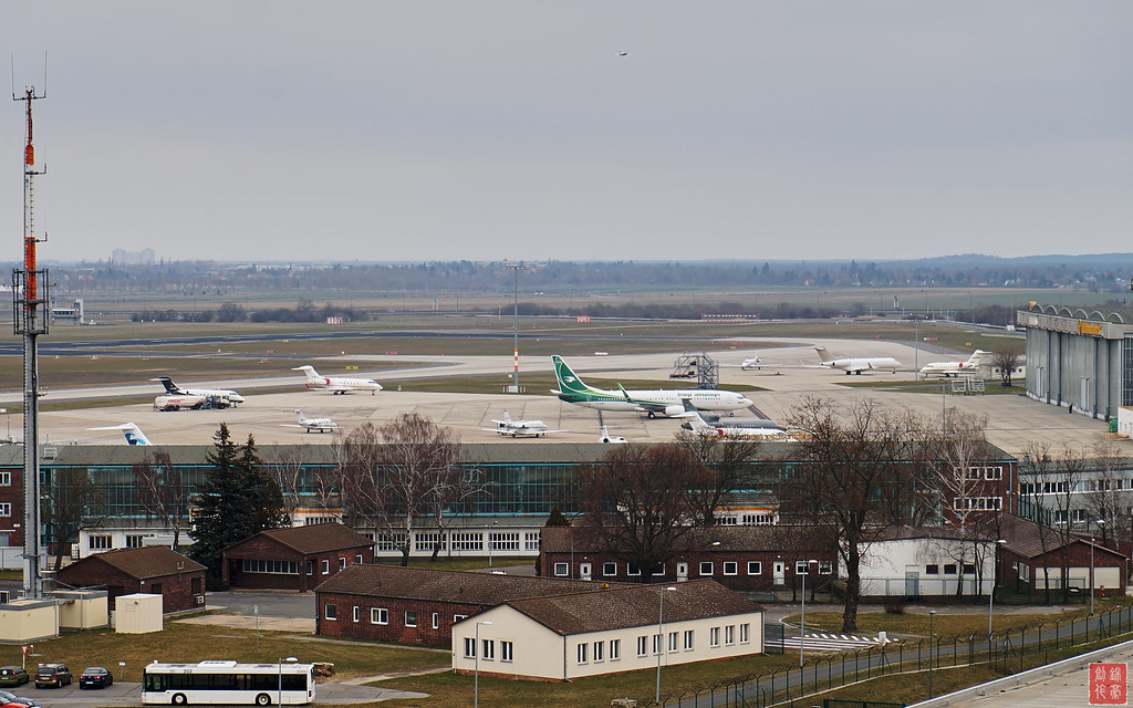 Mehrere Ryanair-Flugzeuge stehen auf dem Vorfeld eines Flughafens mit Start- und Landebahn im Hintergrund.