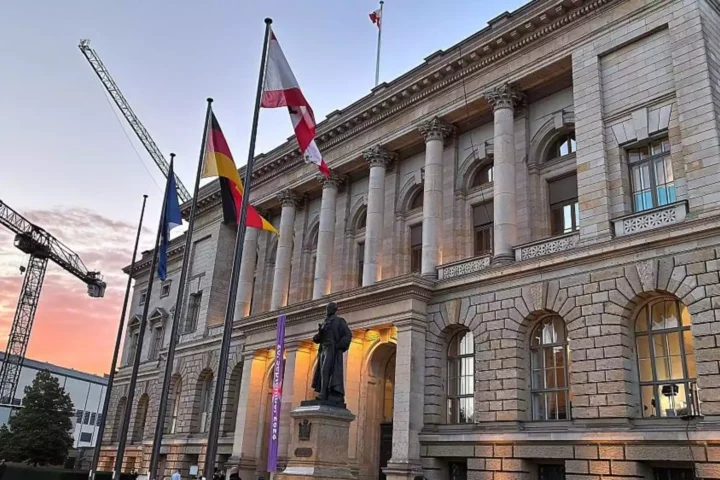 Das Alte Museum in Berlin bei Sonnenuntergang mit mehreren Flaggen vor dem Gebäude.