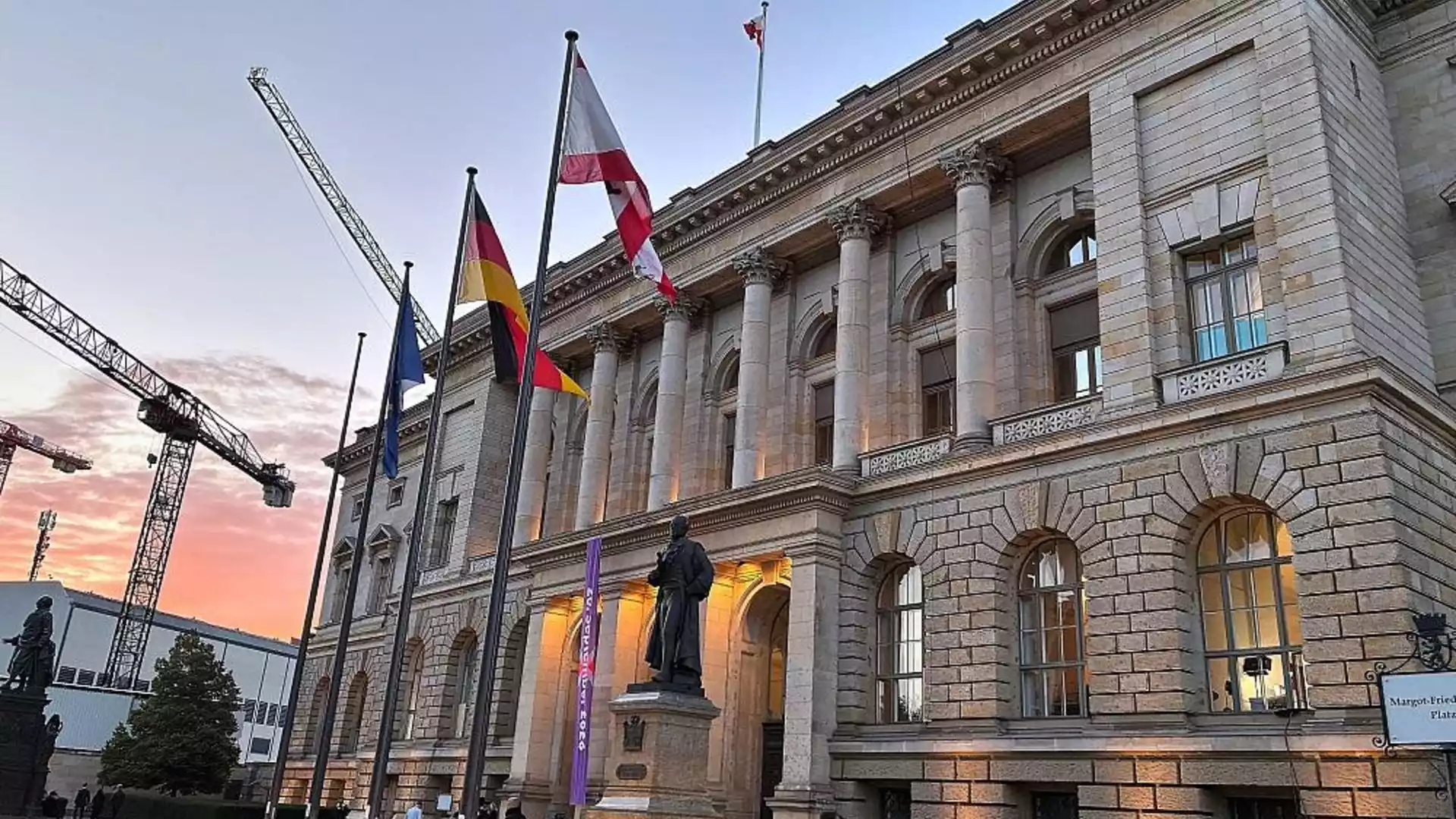 Das Alte Museum in Berlin bei Sonnenuntergang mit mehreren Flaggen vor dem Gebäude.