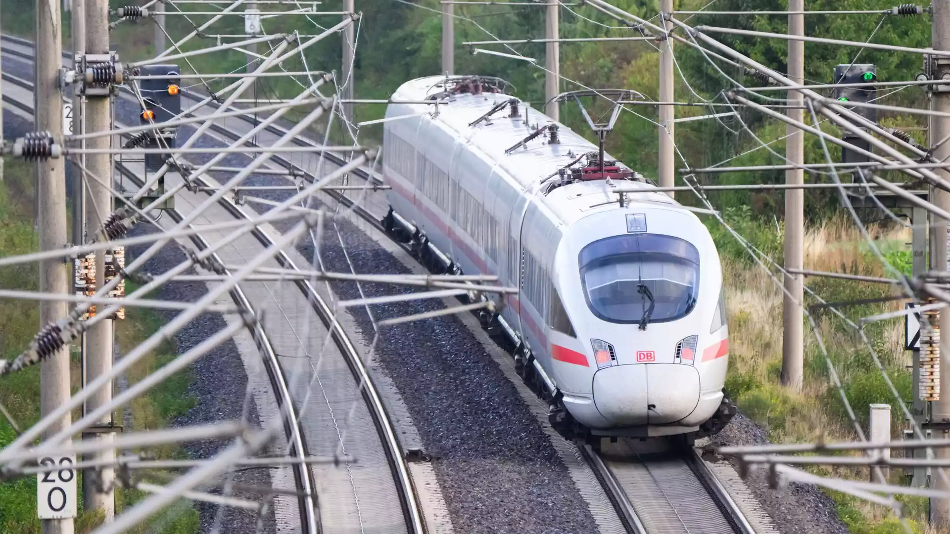 Ein ICE der Deutschen Bahn fährt auf einer elektrifizierten Bahnstrecke unter zahlreichen Oberleitungen.