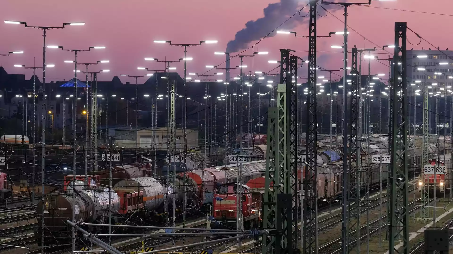 Bundesregierung hebt Wachstumsprognose für 2026 auf 1,3 Prozent an 1 Güterzüge und Rangiergleise in einem beleuchteten Bahnbetriebswerk bei Abendhimmel.