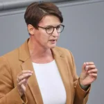 Eine Frau mit Brille spricht im Plenarsaal und gestikuliert mit beiden Händen.