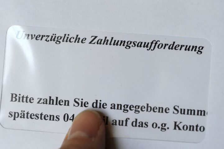 Finger zeigt auf eine deutsche Zahlungsaufforderung mit dem Hinweis „Unverzügliche Zahlungsaufforderung“.