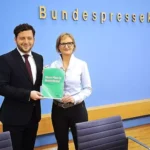 Felix Banaszak und Franziska Brantner halten einen Grünen-Antrag vor der Wand der Bundespressekonferenz.