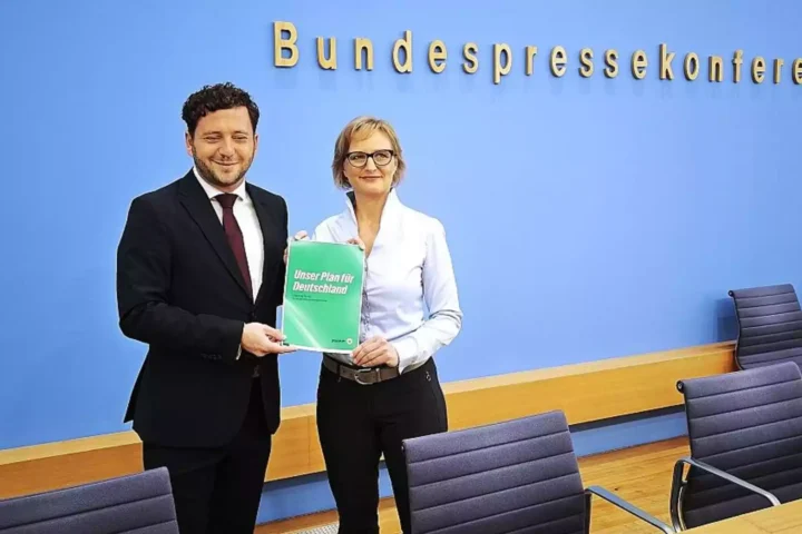 Felix Banaszak und Franziska Brantner halten einen Grünen-Antrag vor der Wand der Bundespressekonferenz.