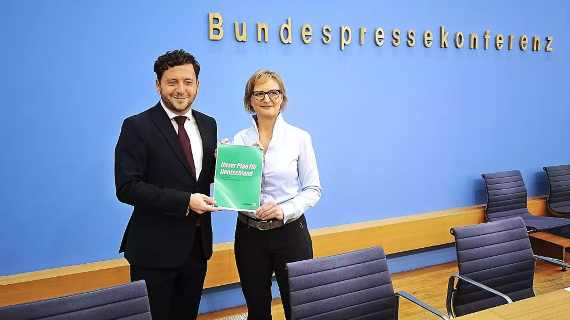 Felix Banaszak und Franziska Brantner halten einen Grünen-Antrag vor der Wand der Bundespressekonferenz.