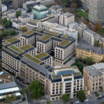 Luftaufnahme eines modernen Gebäudekomplexes mit begrünten Dächern; am unteren Bildrand ist ein Crédit-Agricole-Gebäude zu sehen.